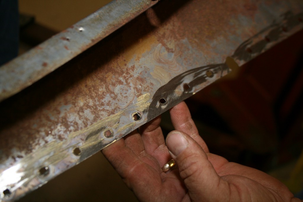 6. Again using the die-grinder, the original star-punch holes were ground off, leaving a flat uniform surface to mount the new panel with. We also hit the metal with a scotch-brite Roloc pad on a die-grinder to clean up the surface rust and residual adhesive.