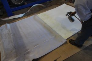11. Next, we laid the vinyl onto the headliner, folded half of it back and sprayed some more glue down. The shop was kind of chilly when we did this, so we used a heat gun on low to warm up the vinyl and glue before moving on.