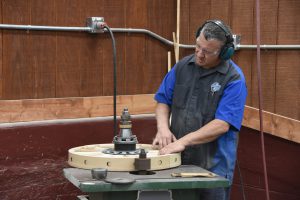 The machine that cuts the spokes offers a solid mounting point for the wheel, so that the finished wheel is perfectly round. Jonathan measures several times during this process to ensure correct sizing.